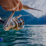 Person fishing with spinning reel on lake