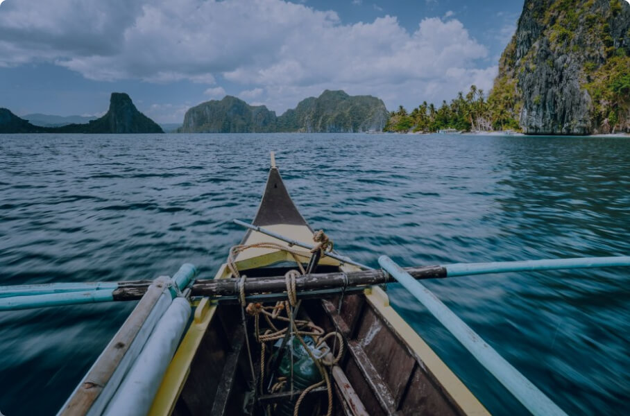 Outrigger boat heading toward tropical limestone islands